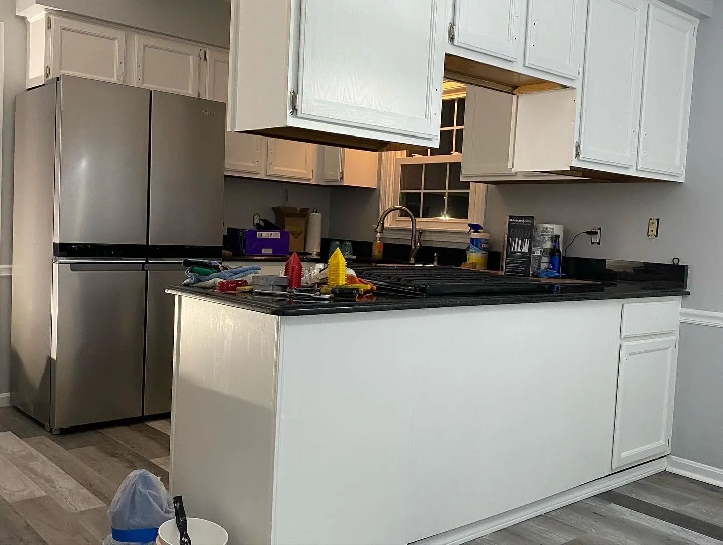 A kitchen with white cabinets and a stainless steel refrigerator.