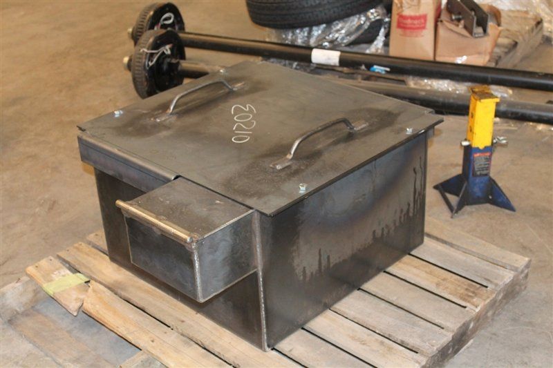 A dark metal box with a lid and handles, likely for industrial use, sitting on a wooden pallet.