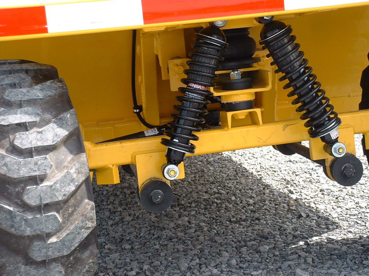 Yellow vehicle with shock absorbers and a large tire.