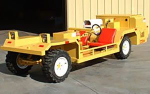 Yellow airport baggage tractor with red seat, parked outside.