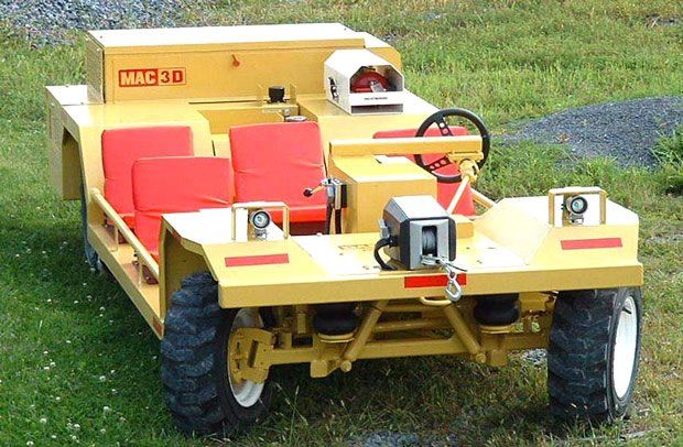 Yellow MAC 20 utility vehicle with red seats and large tires, parked on grass.