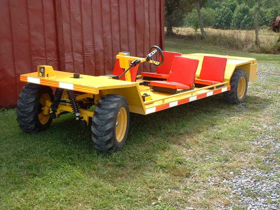 Yellow farm vehicle with large tires and red seating parked on grass.