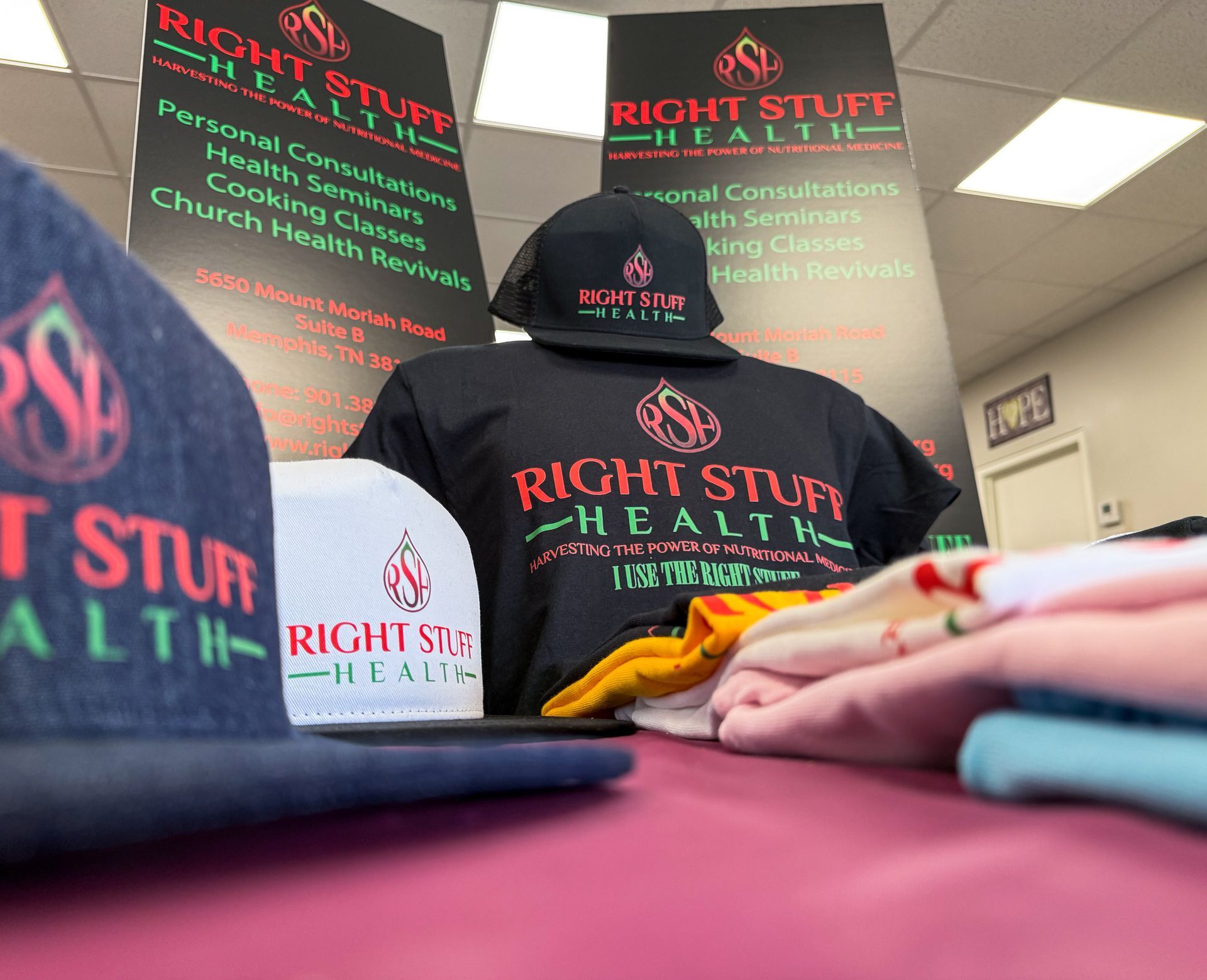 A bunch of hats and shirts are on a table for right stuff health