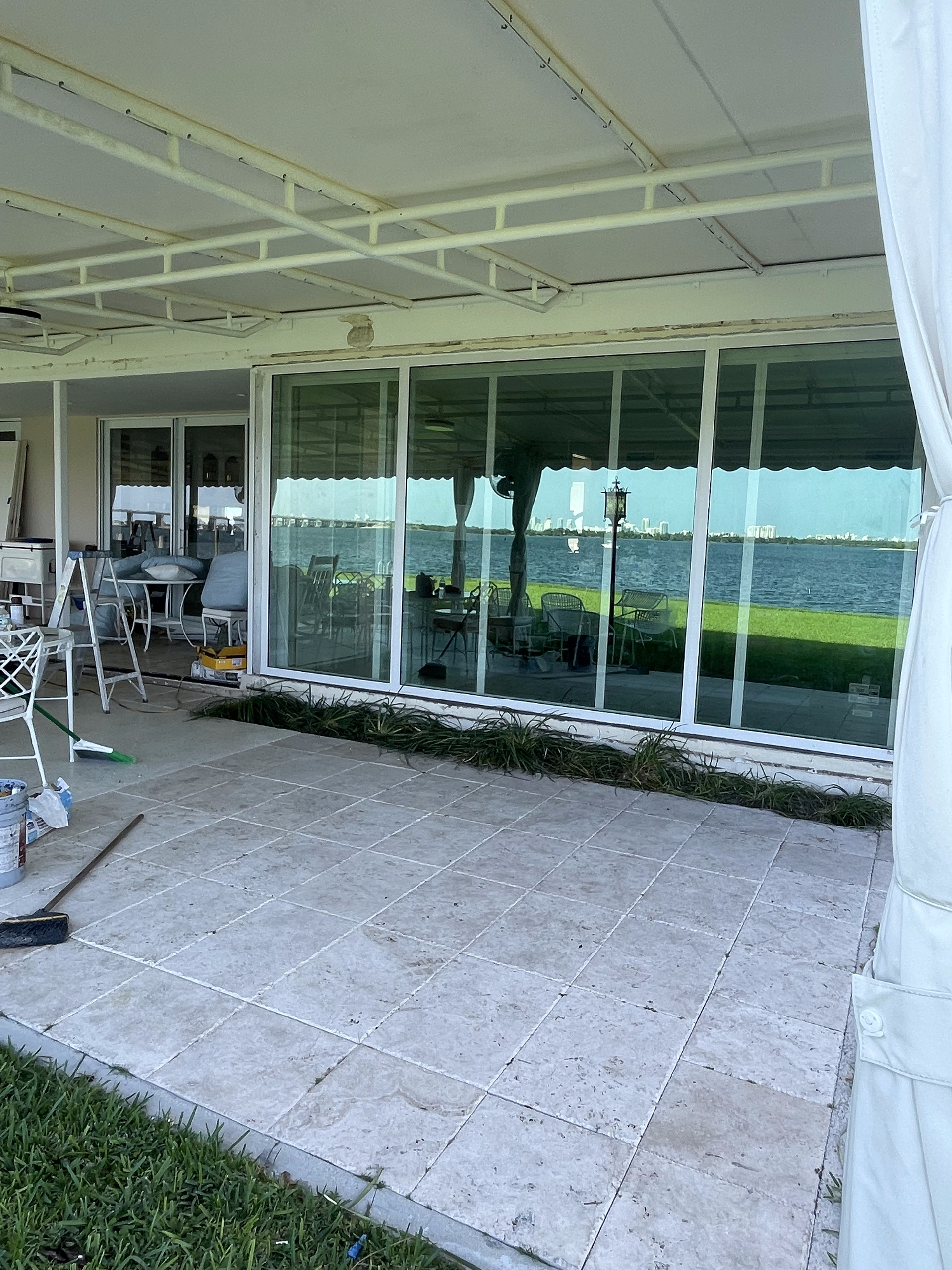 Patio with sliding glass doors, concrete flooring, and outdoor seating under a white roof.