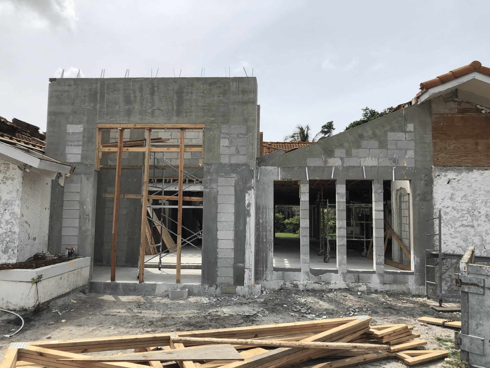 Construction of a building with concrete block walls, wooden frames, and an existing tiled roof.