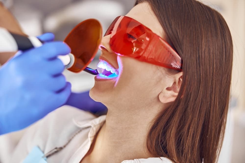 A Woman is Getting Her Teeth Whitened by a Dentist — Advanced Dental Southern Highlands in Moss Vale, NSW