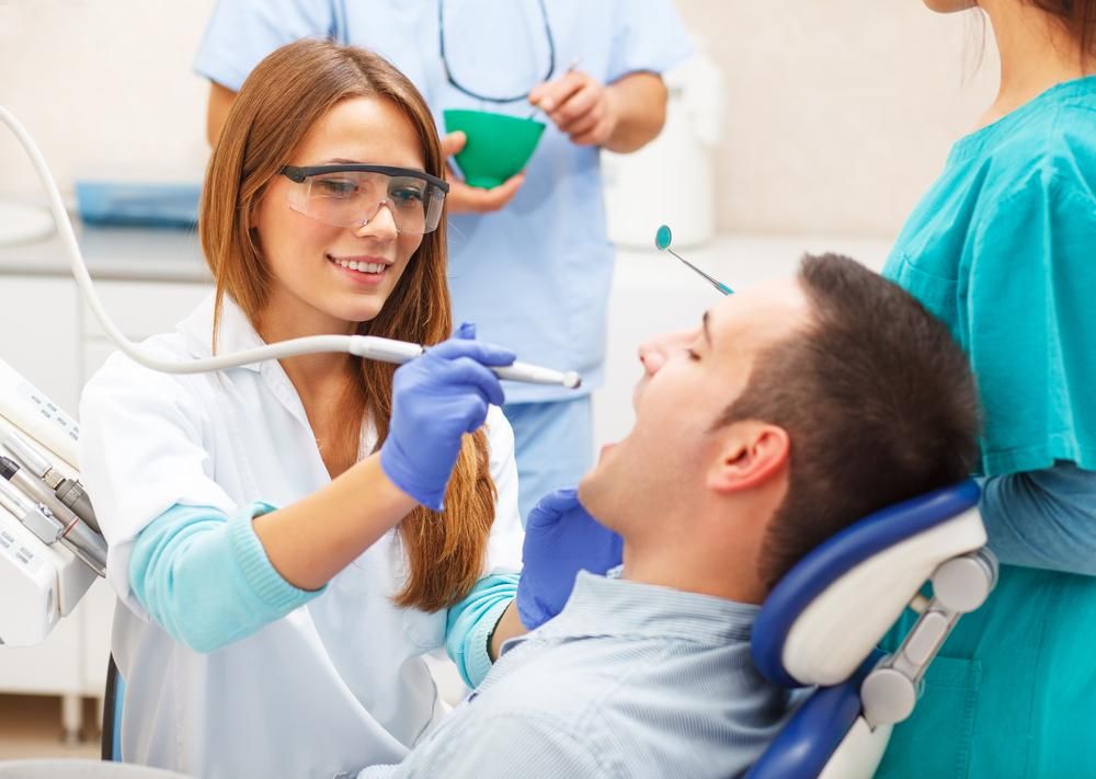 A Man Is Sitting in A Dental Chair Getting His Teeth Examined by A Female Dentist — Advanced Dental Southern Highlands in Moss Vale, NSW