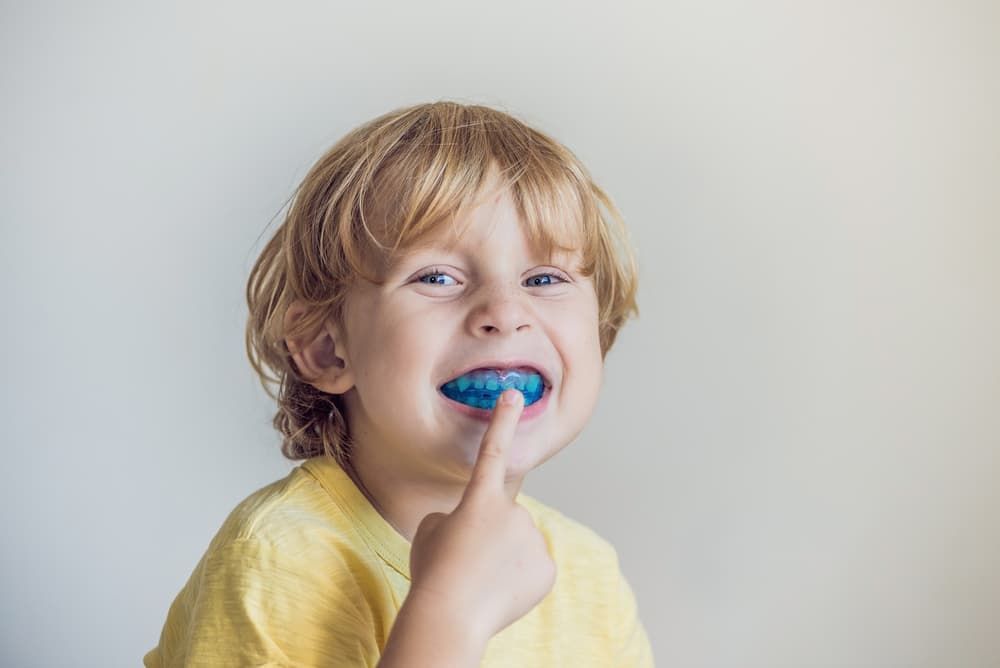 A Young Boy is Wearing a Blue Mouth Guard and Smiling — Advanced Dental Southern Highlands in Moss Vale, NSW