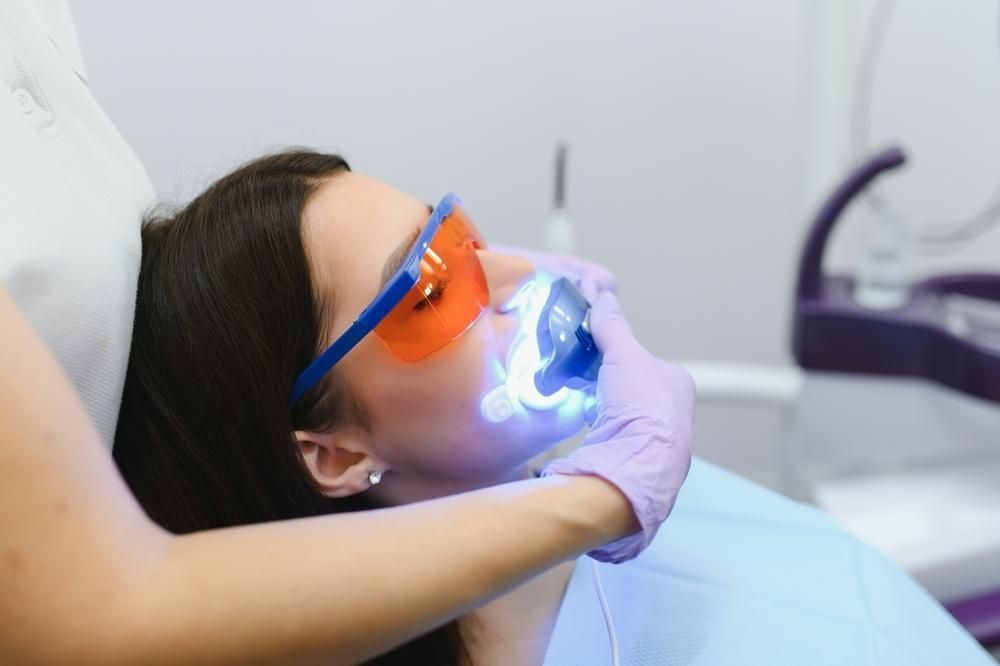 A Woman Is Getting Her Teeth Whitened by A Dentist — Advanced Dental Southern Highlands in Moss Vale, NSW