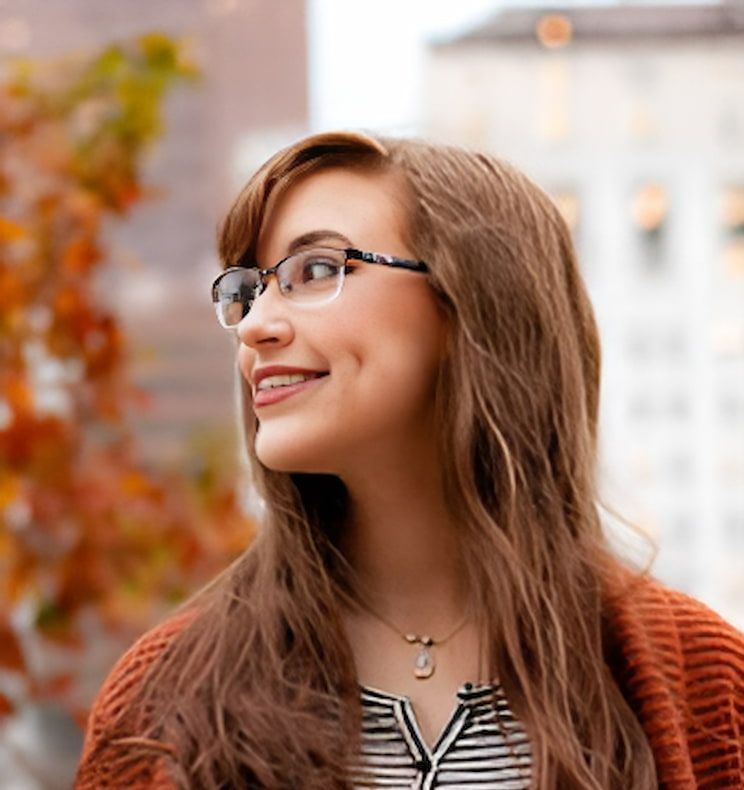A Woman Wearing Glasses and a Striped Shirt is Smiling — Advanced Dental Southern Highlands in Moss Vale, NSW