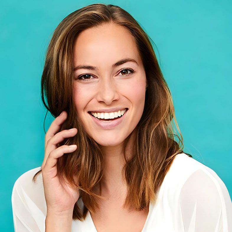 A Womanis smiling at the camera with a green background — Advanced Dental Southern Highlands in Moss Vale, NSW
