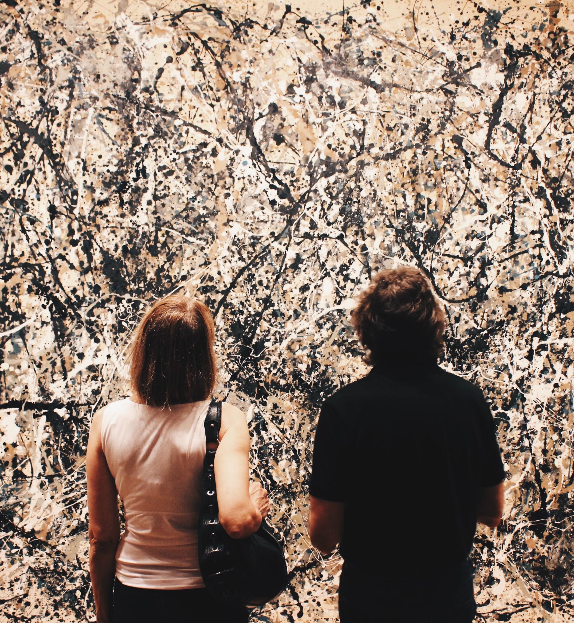 Two people staring at an artwork made from splashes of paint