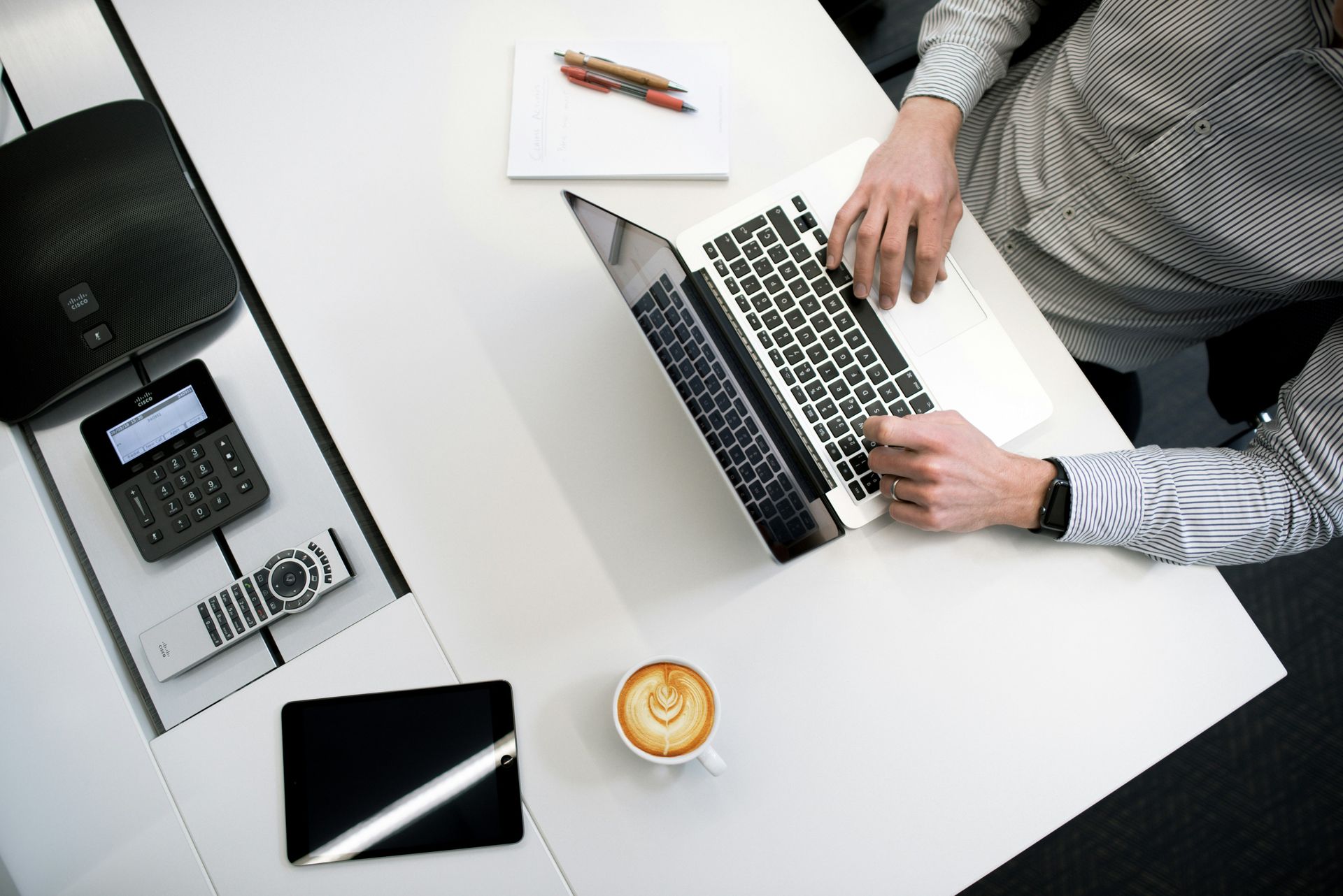 Person sitting at an office desk, typing on a laptop