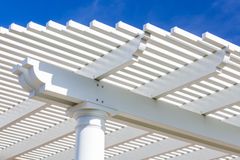 White pergola with slatted roof against a clear blue sky.