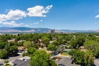 Aerial view of a suburban neighborhood under a blue sky with fluffy clouds, mountains in the distance.