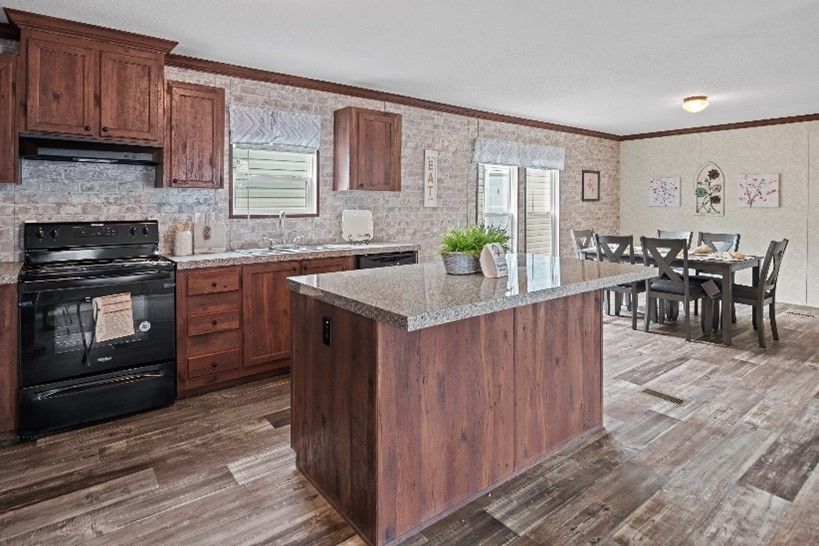 Spacious kitchen with dark wood cabinets, a granite countertop island, and dining area with a table and chairs.