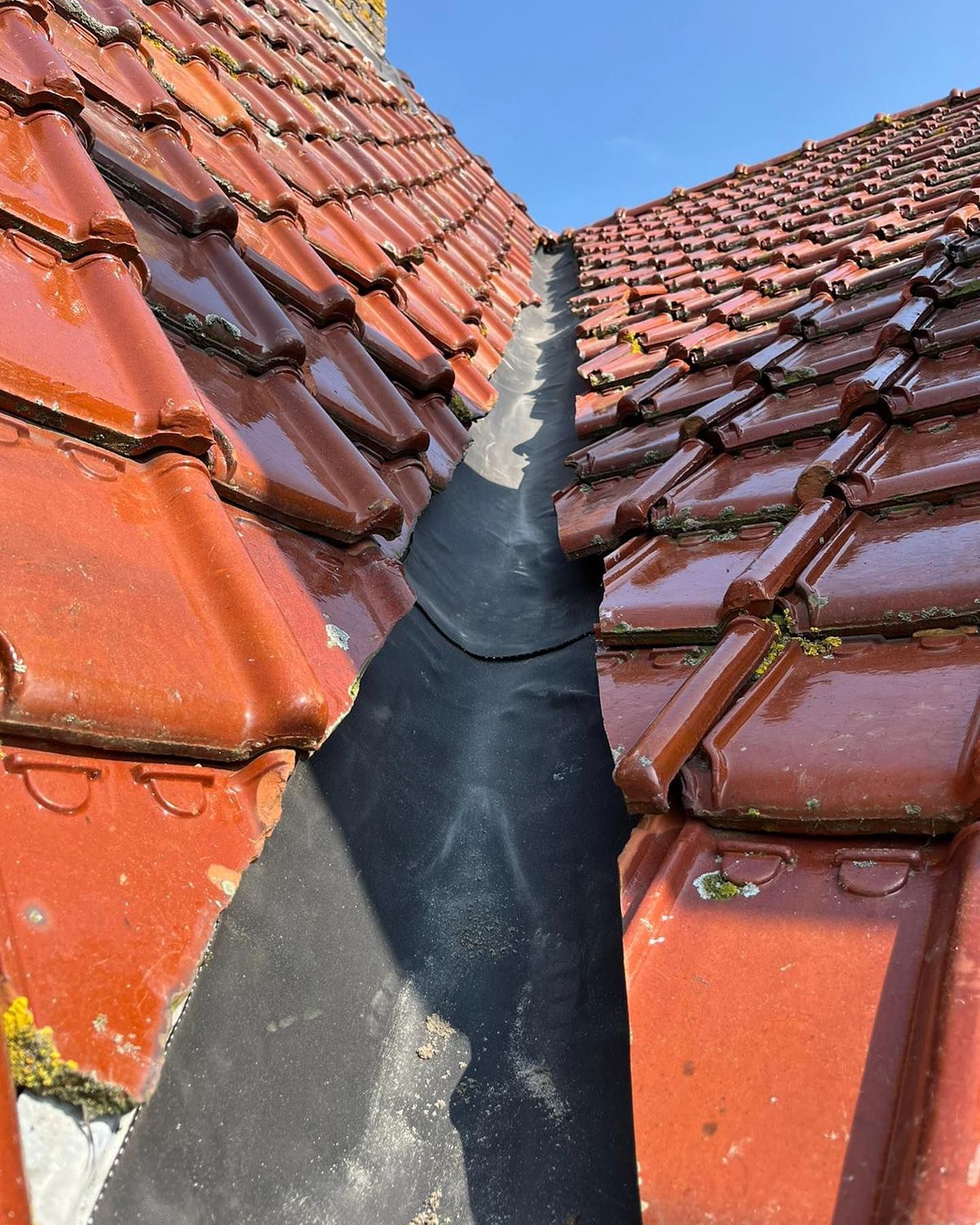 een dak met rode pannen en een zwarte goot