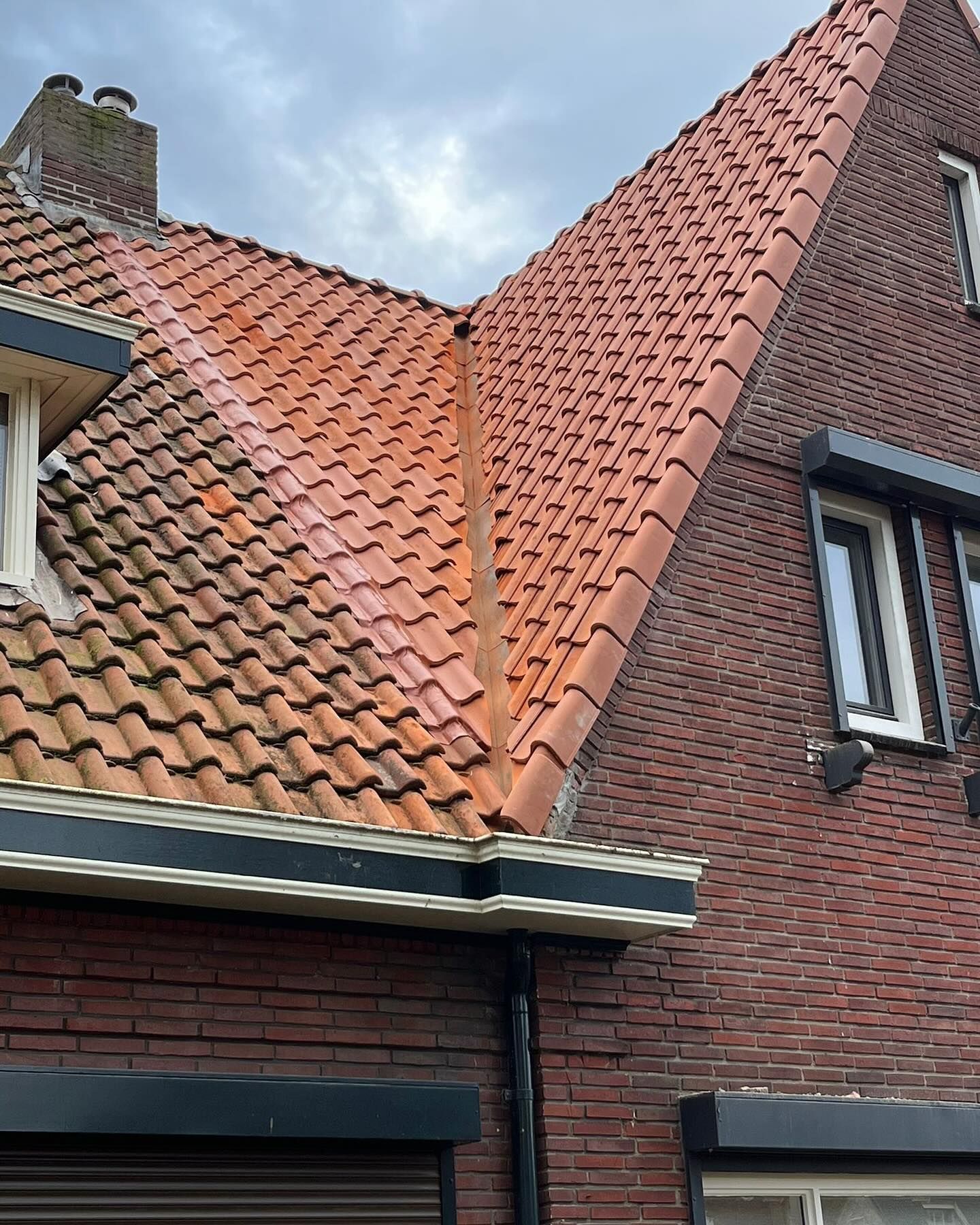 een bakstenen gebouw met een rood pannendak en twee ramen