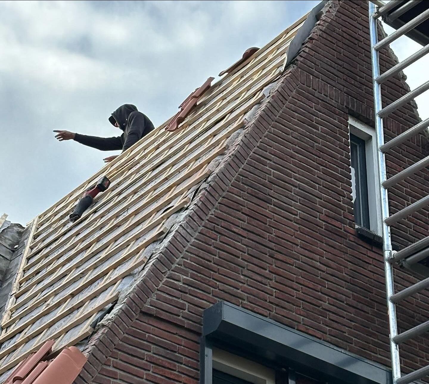 een man werkt op het dak van een bakstenen gebouw.
