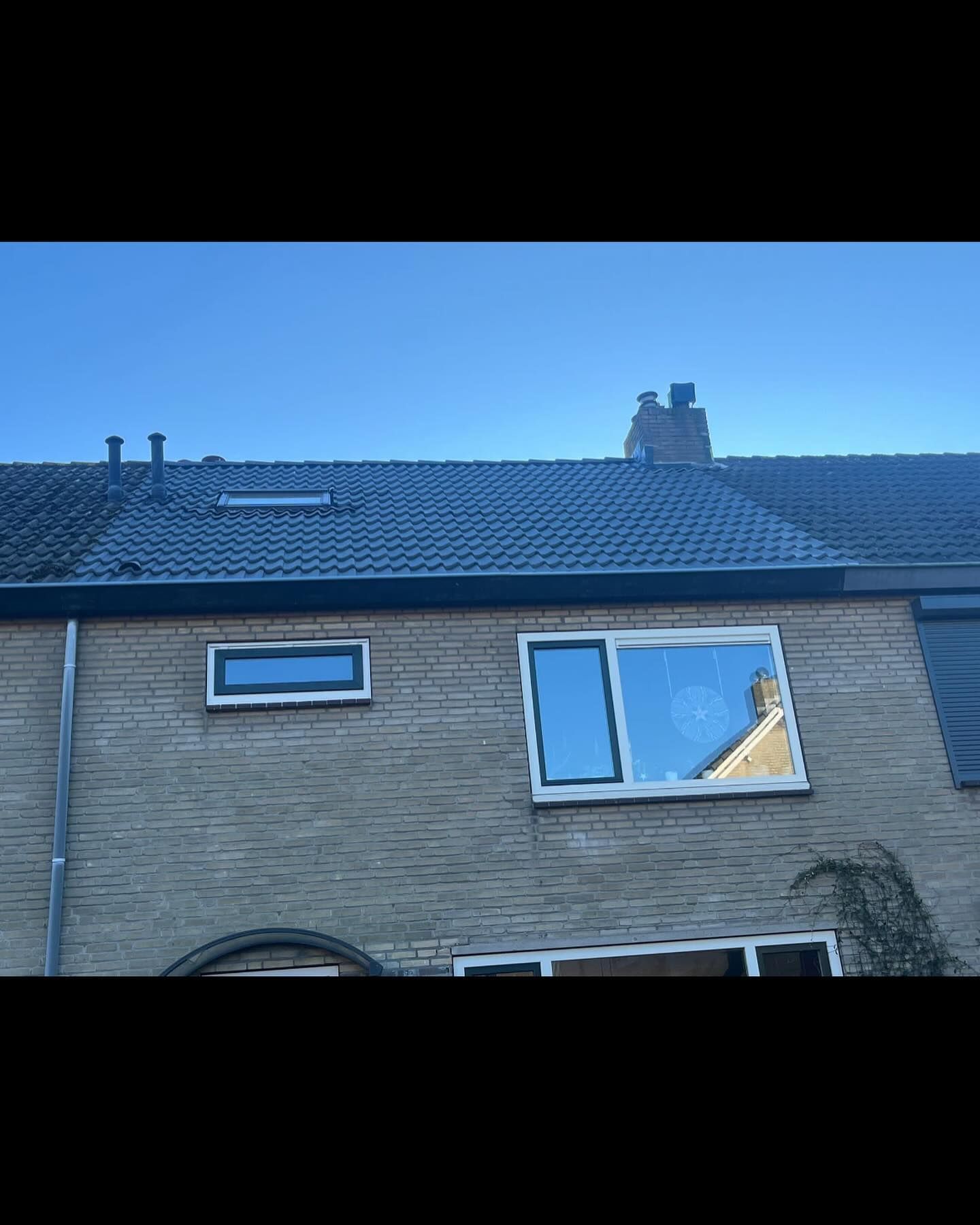 een bakstenen huis met een dak en twee ramen.