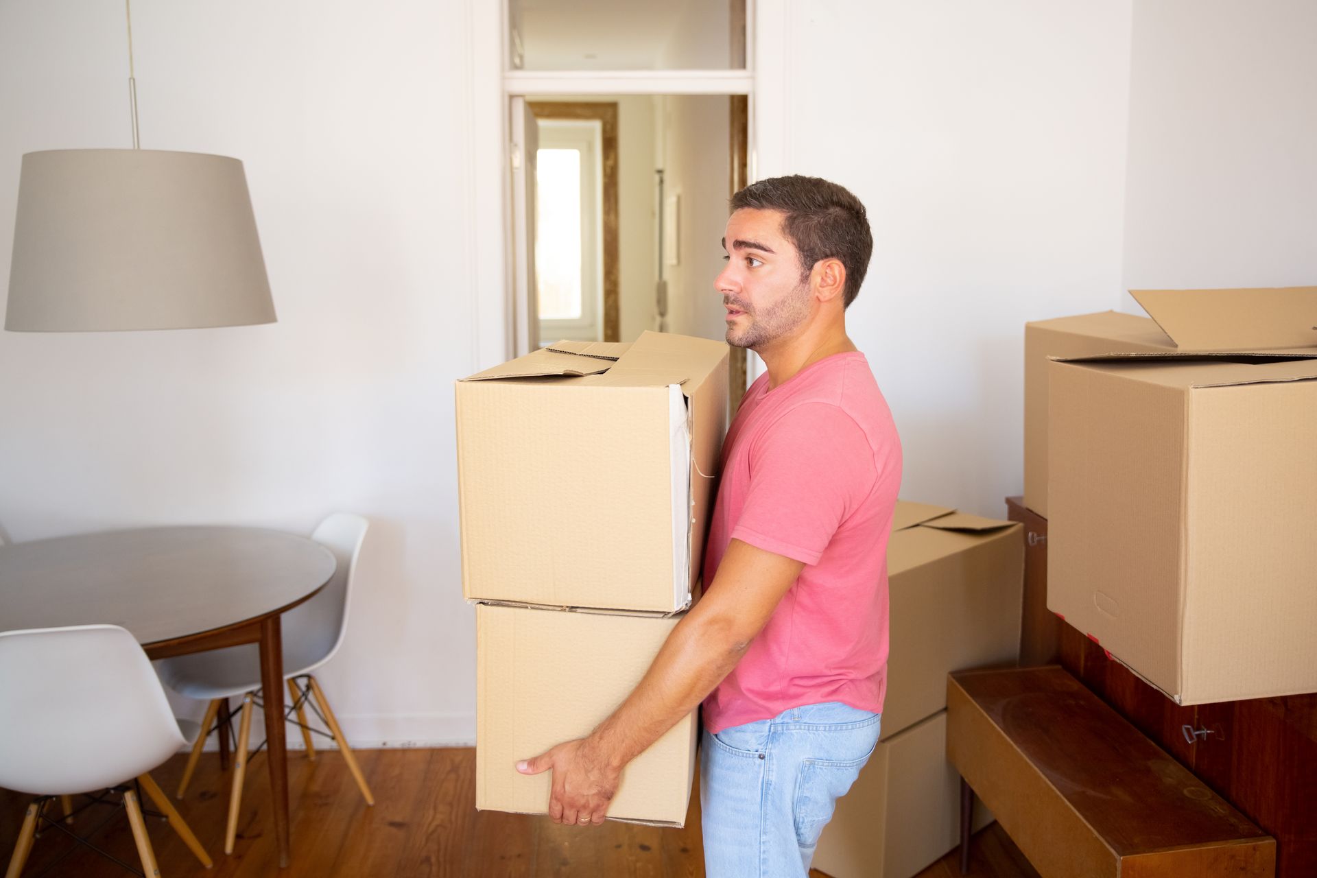 Man carrying two cardboard boxes, moving indoors.