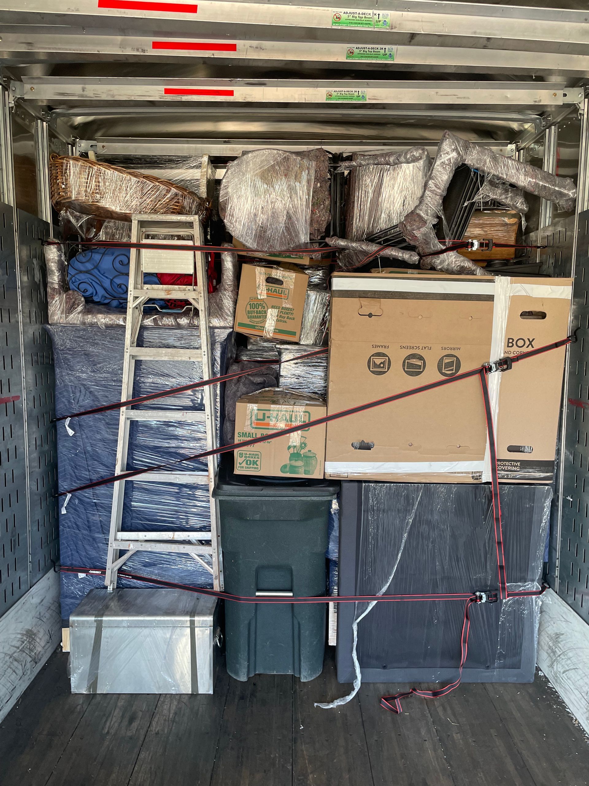 The inside of a moving truck filled with boxes and a ladder.