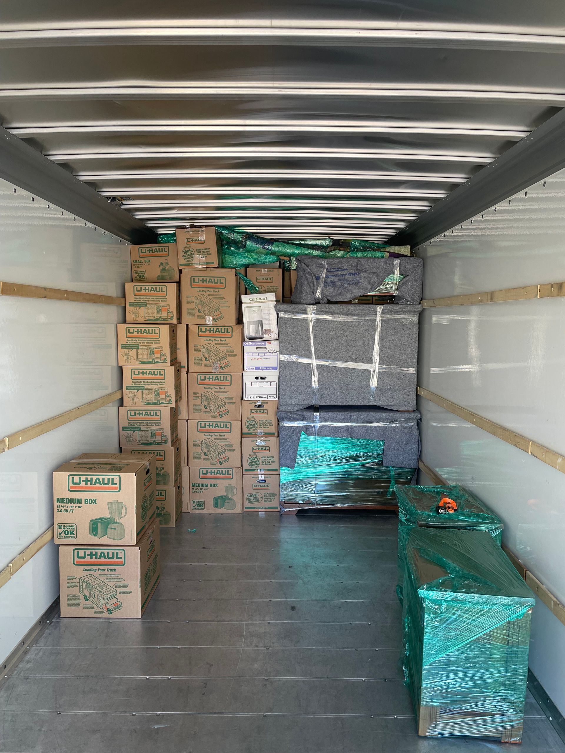 The inside of a moving truck filled with boxes and cushions.