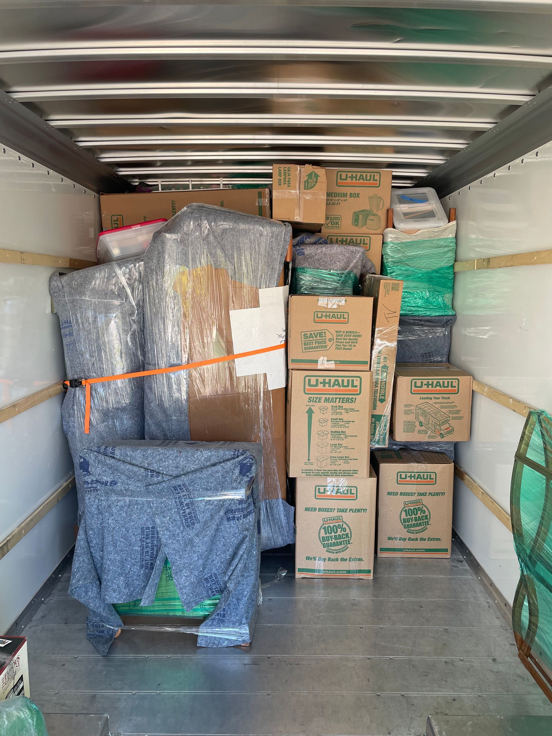 The inside of a moving truck filled with boxes and furniture.