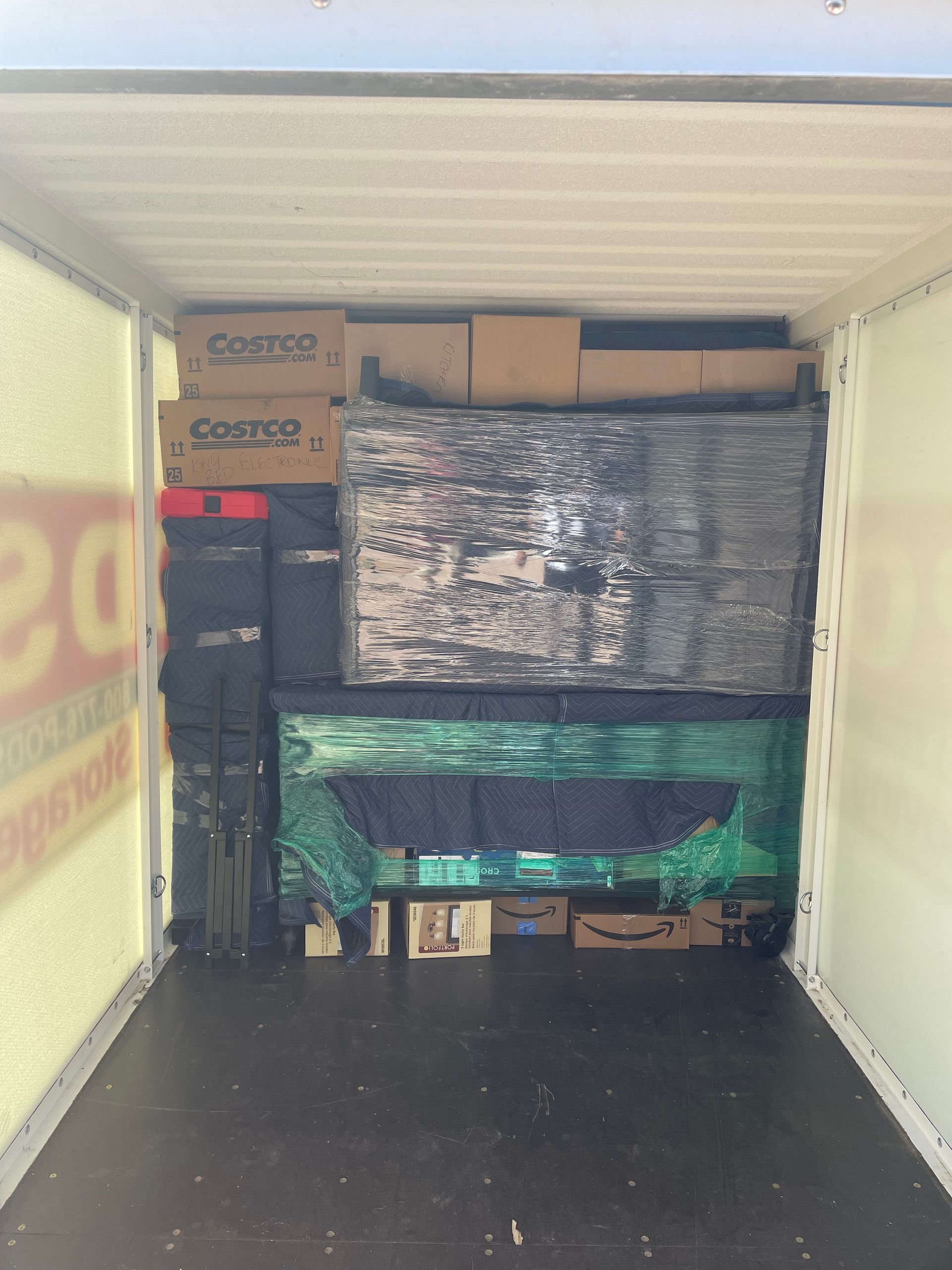 The inside of a moving truck filled with boxes and a green tarp.