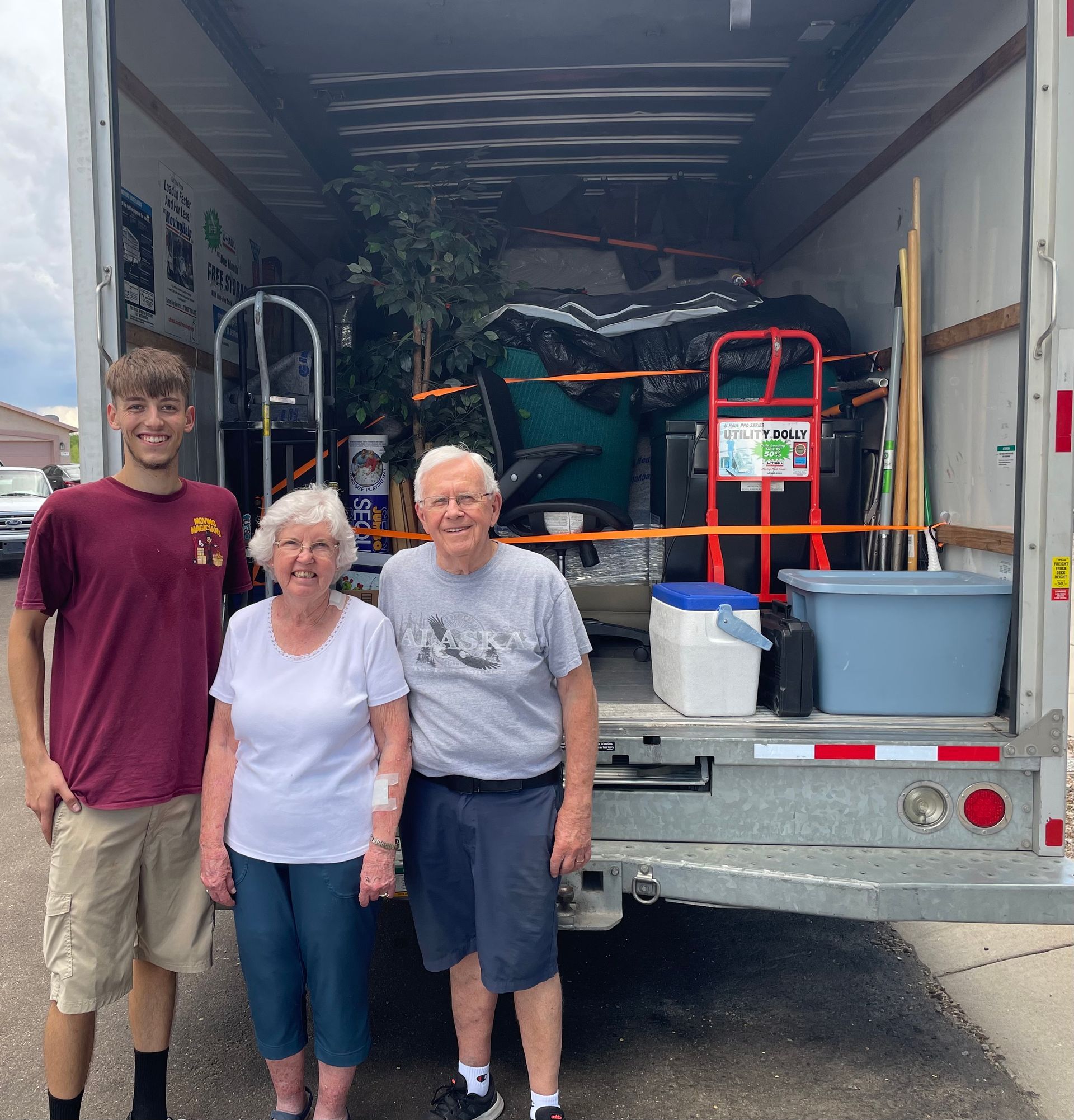 Three people are standing in front of a moving truck