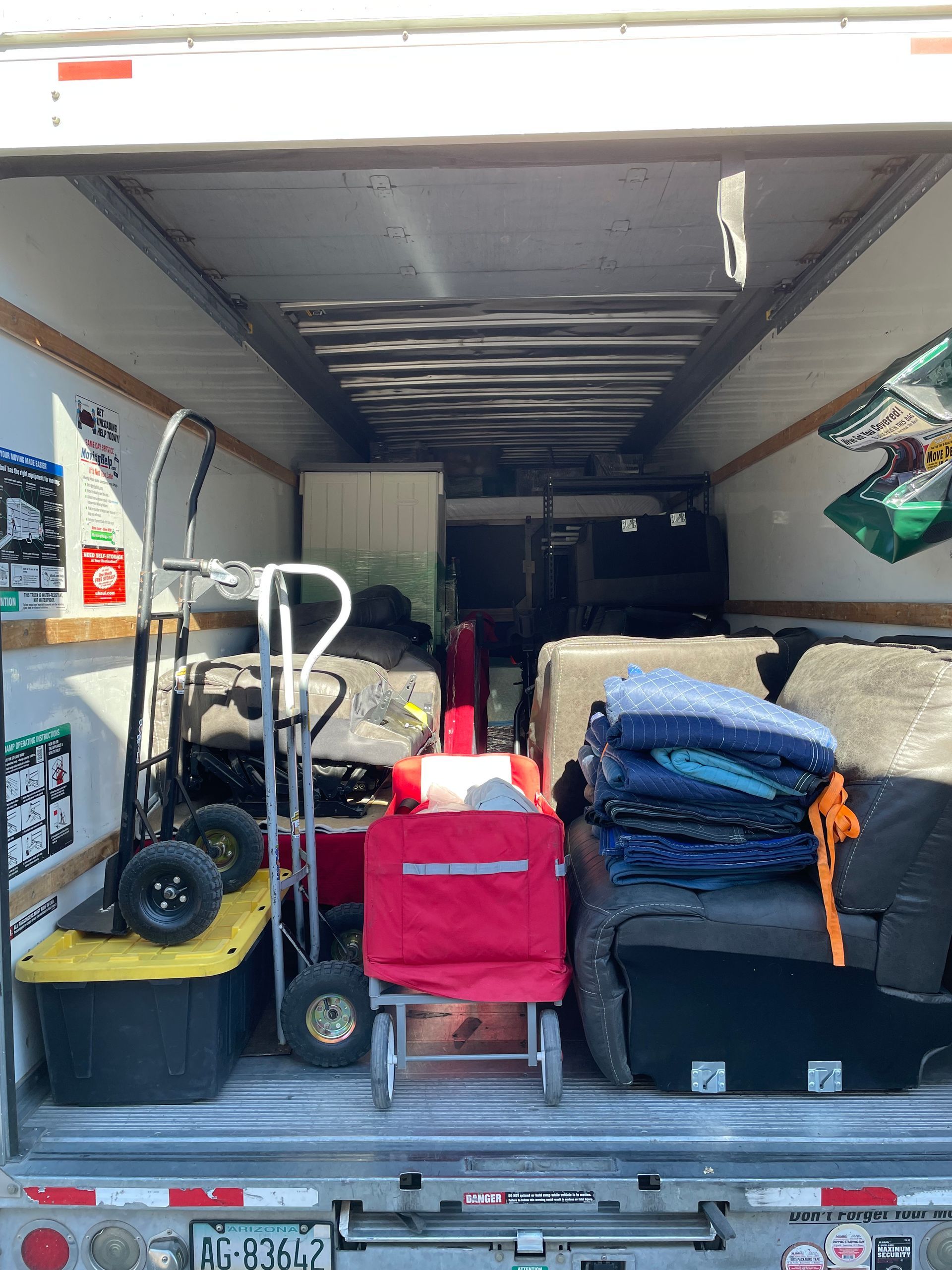 The back of a moving truck is filled with lots of moving supplies.