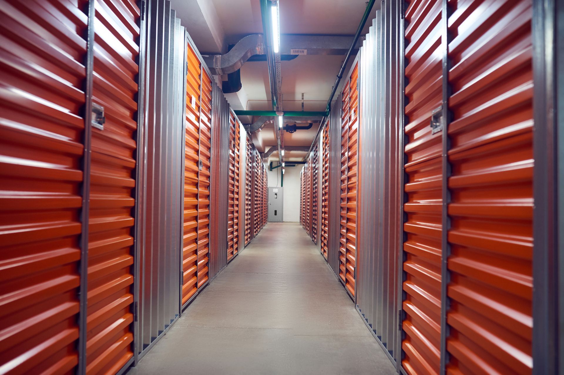 A long hallway filled with orange lockers in a storage facility.