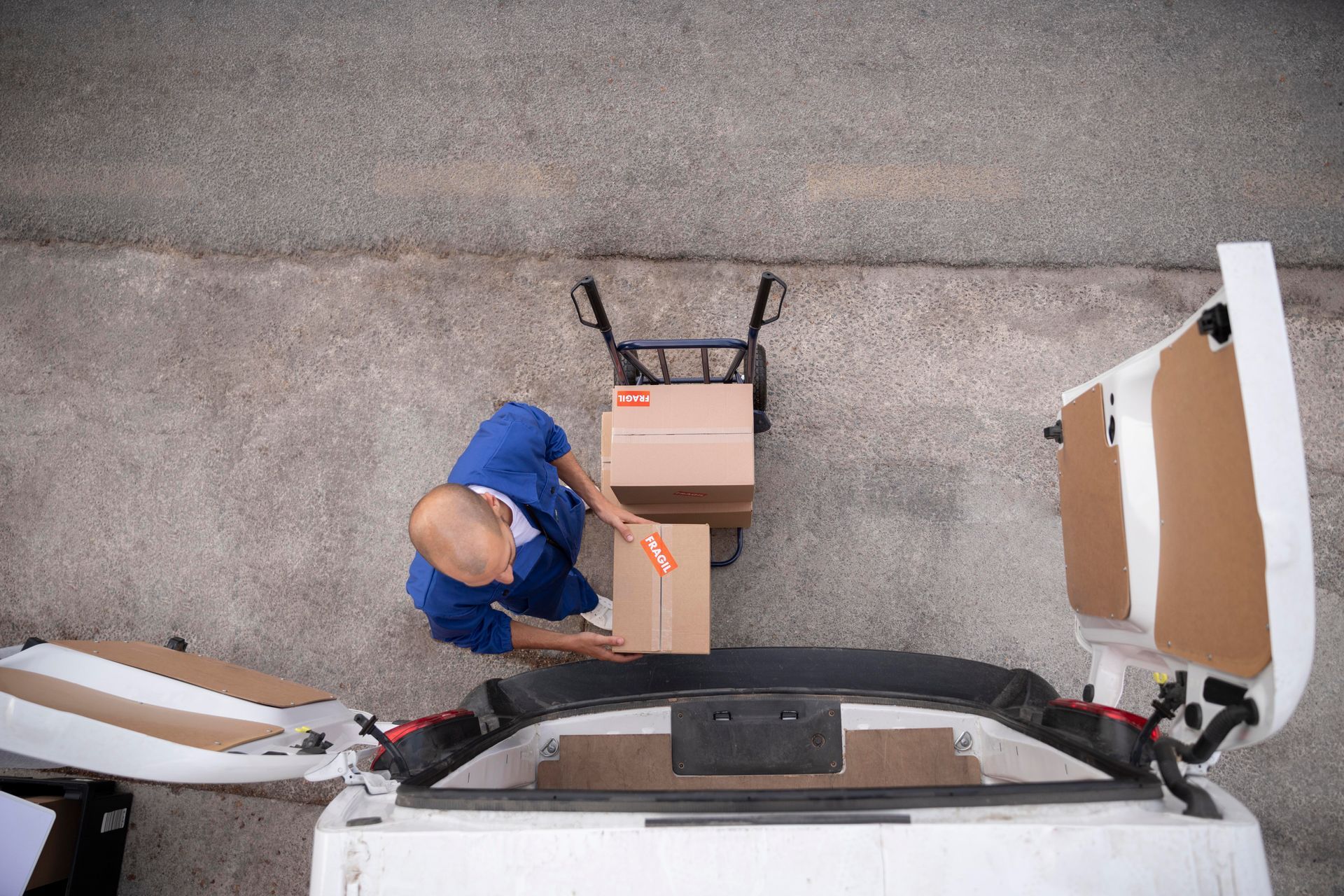 A delivery man is loading boxes into the back of a van.