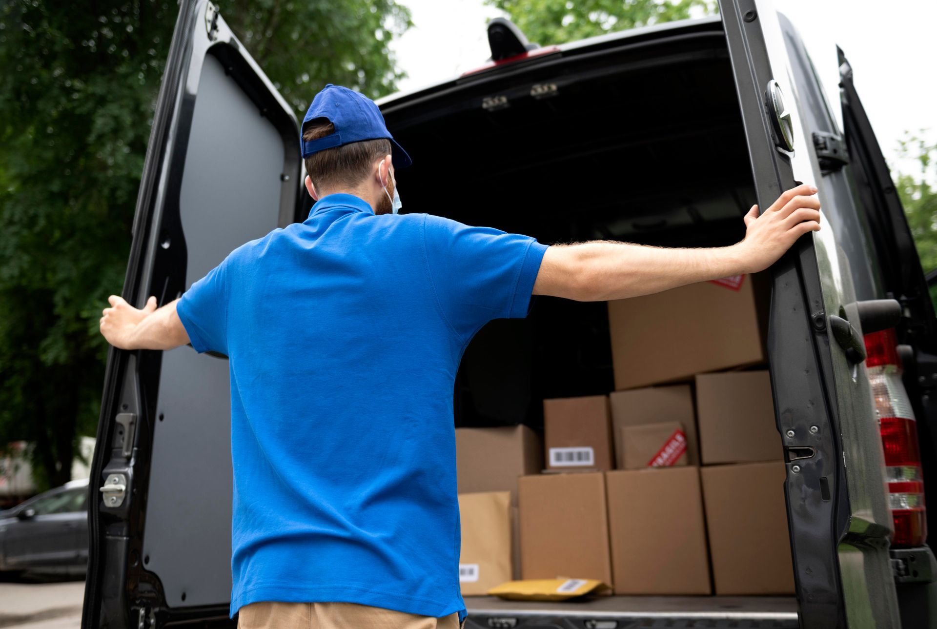 A delivery man is loading boxes into the back of a van.