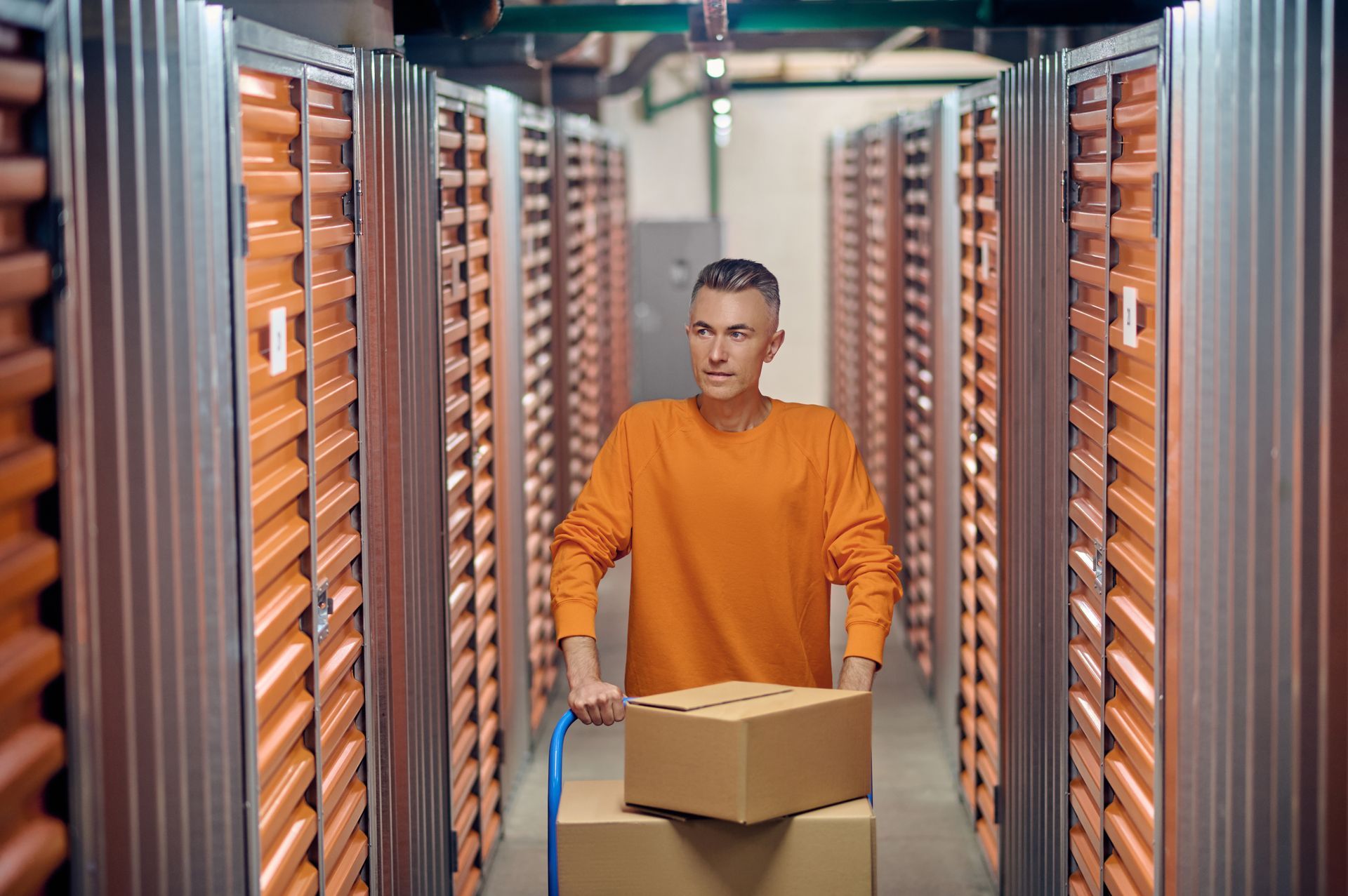 A man is pushing a cart with boxes in a server room.