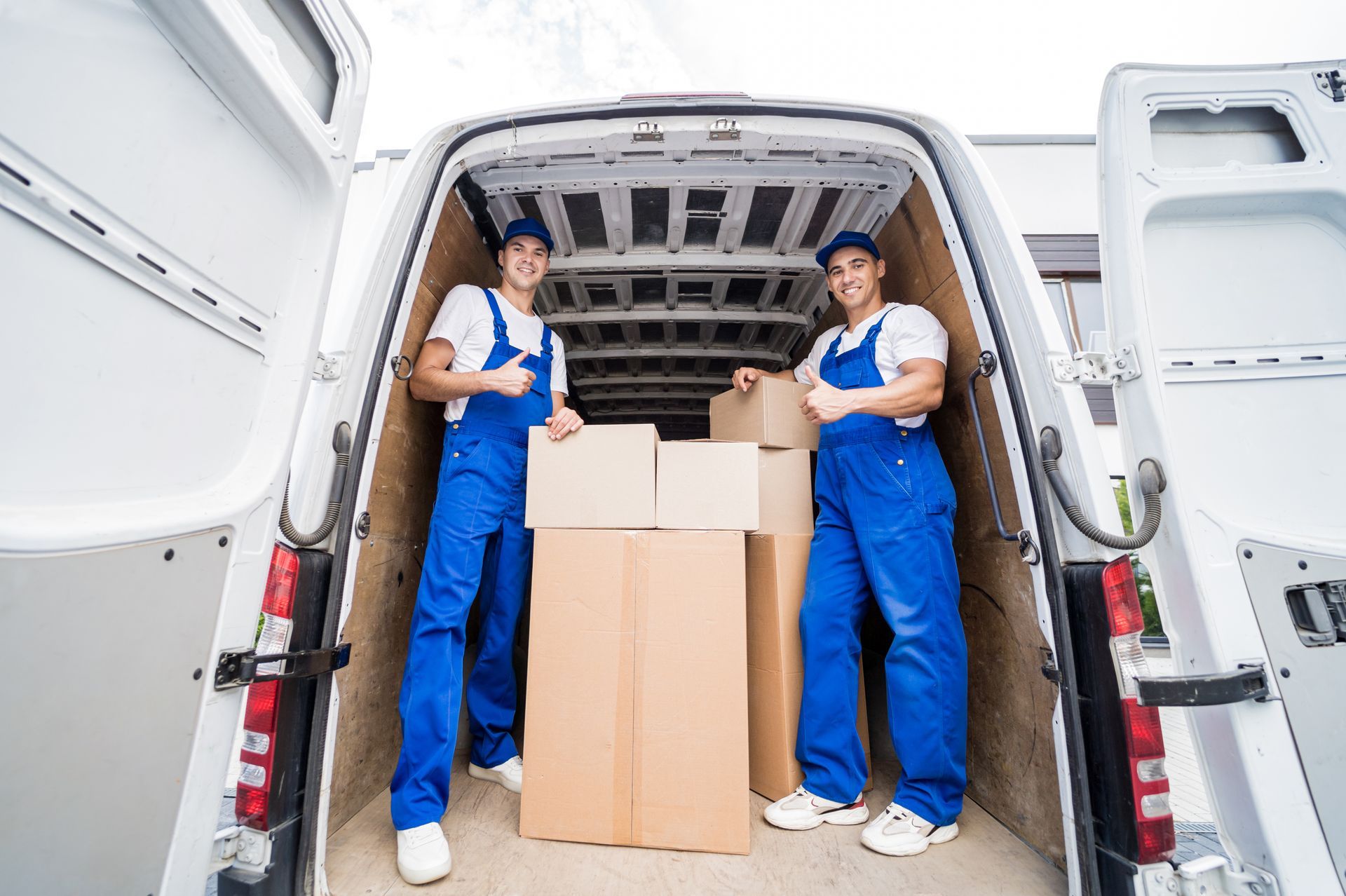 Two movers are loading boxes into a van.