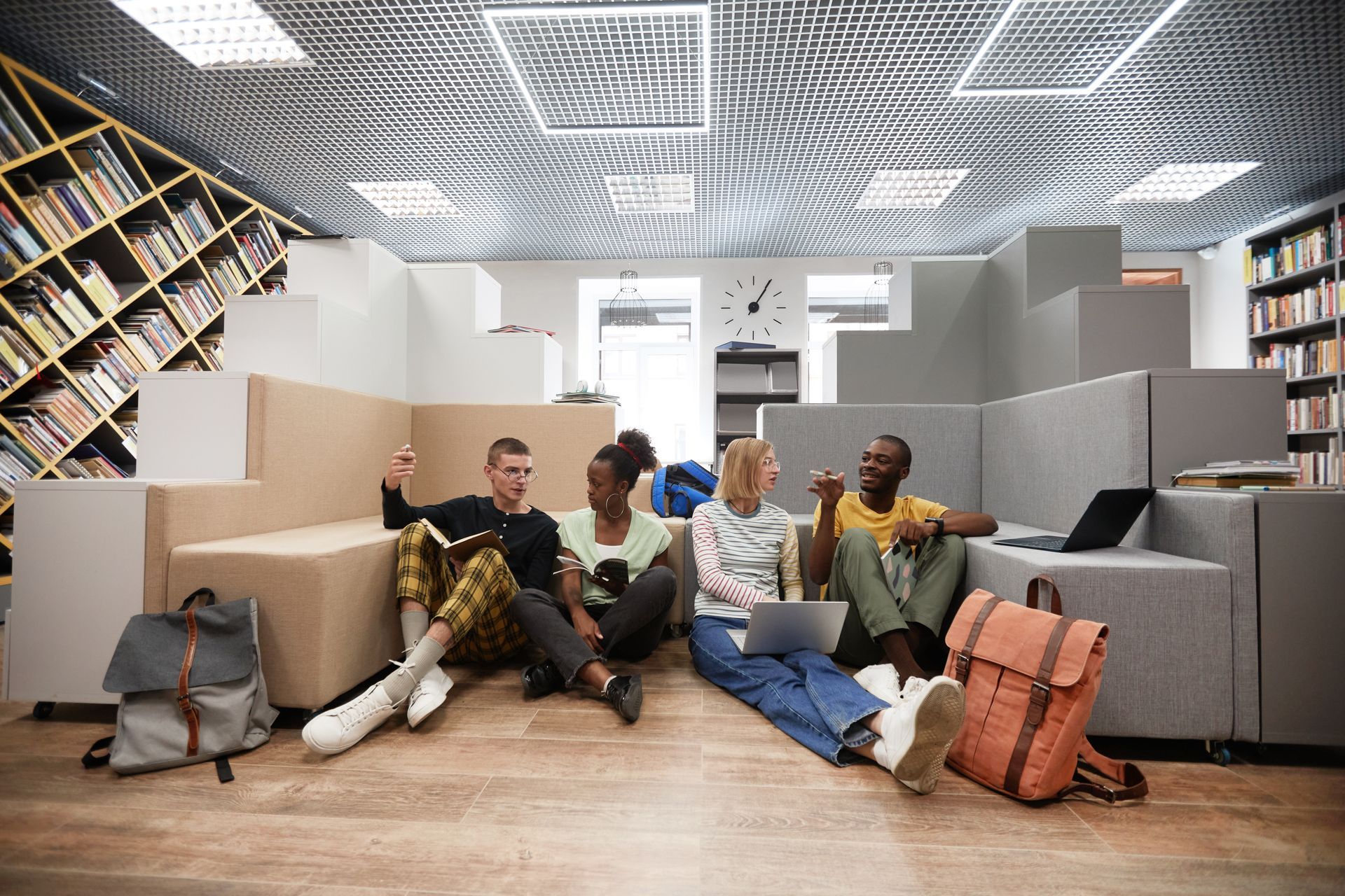 A group of young people are sitting on the floor in a library.