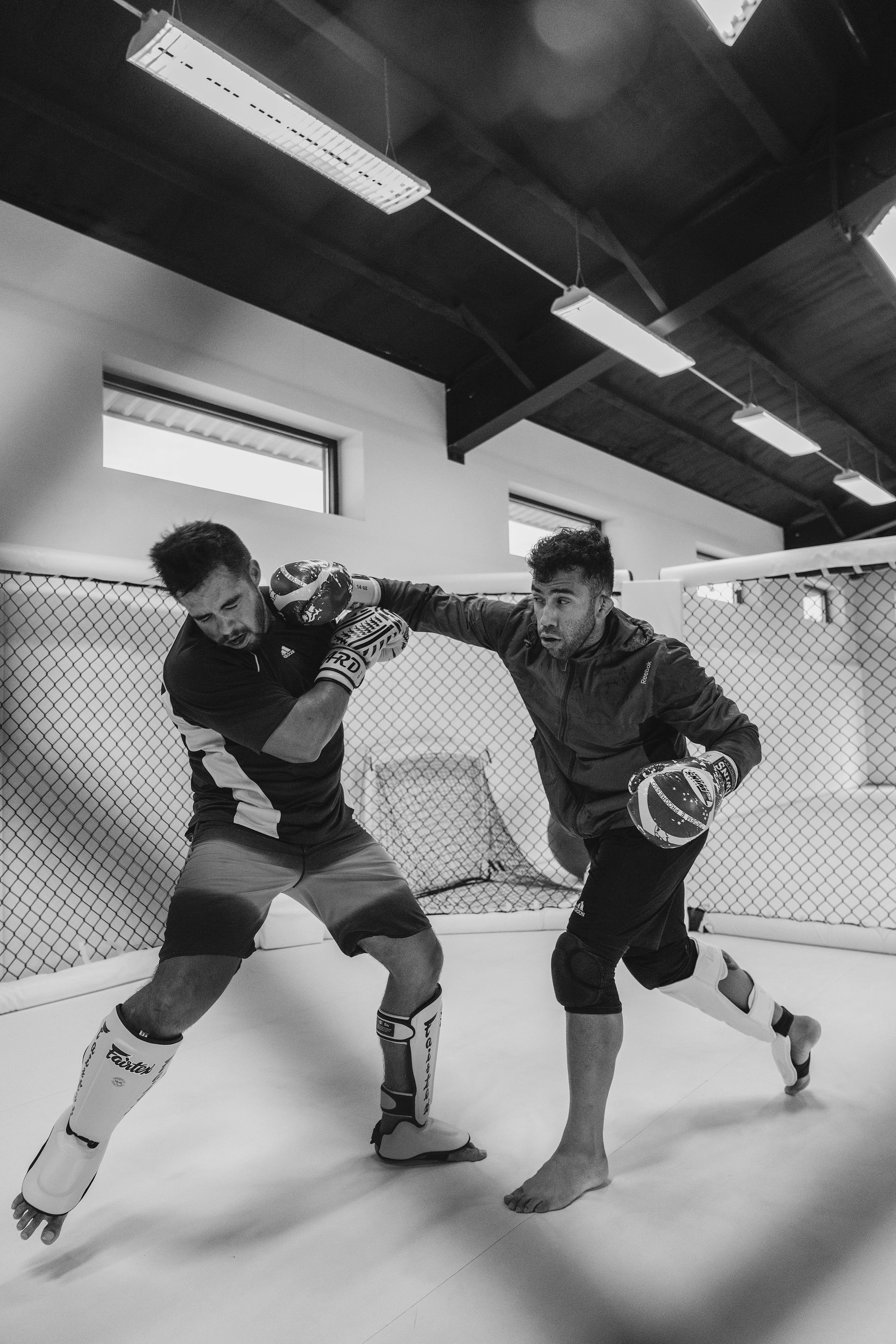 Two men compete in Brazilian Jiu-Jitsu on a mat.