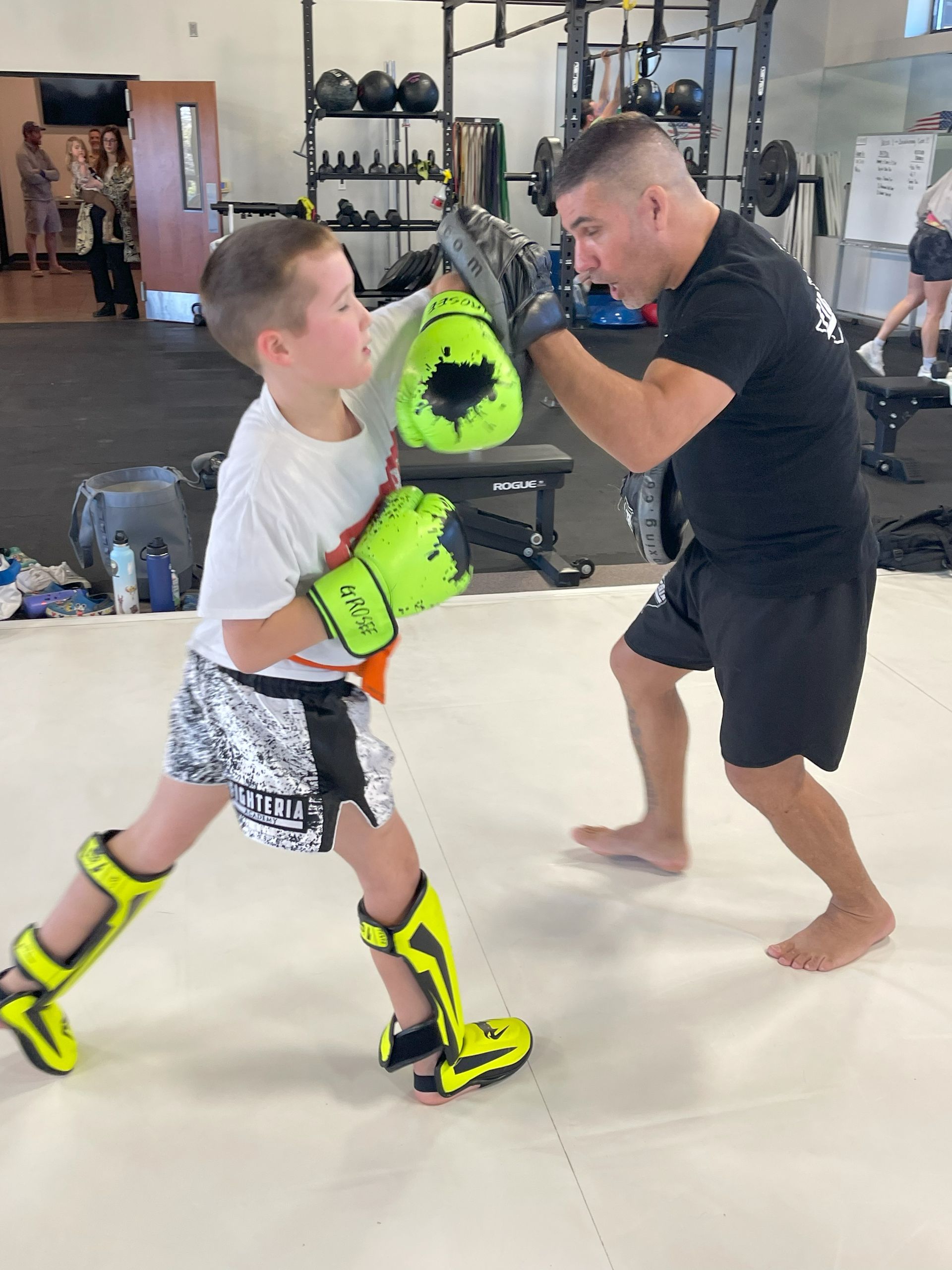 A man and a boy are boxing in a gym.