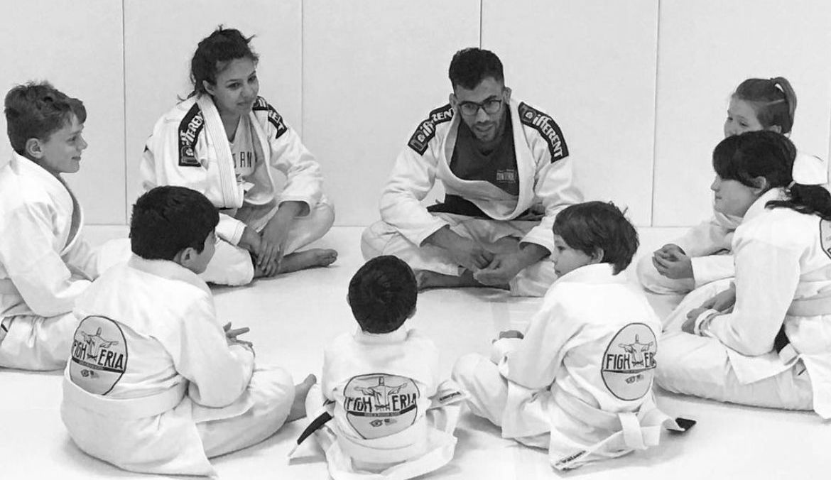 A group of kids are sitting in a circle with a man talking to them.