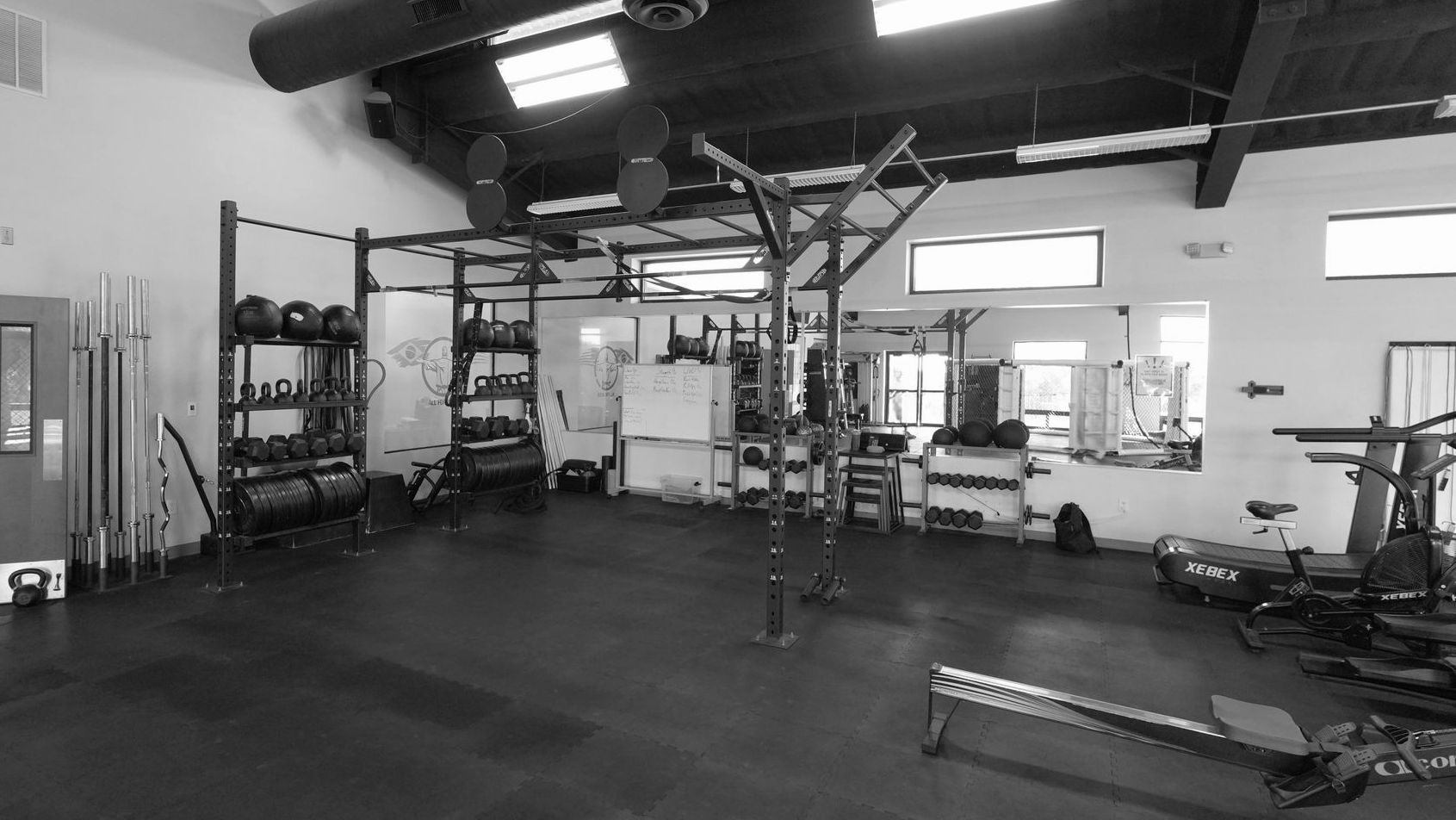 A black and white photo of a gym with a lot of equipment.
