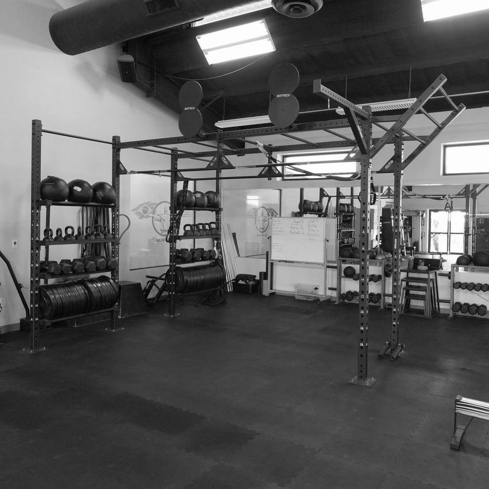 A black and white photo of a gym with a lot of equipment.