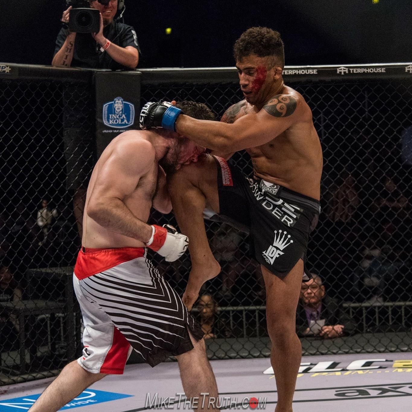 Two men are fighting in a cage and one of them has a tattoo on his arm