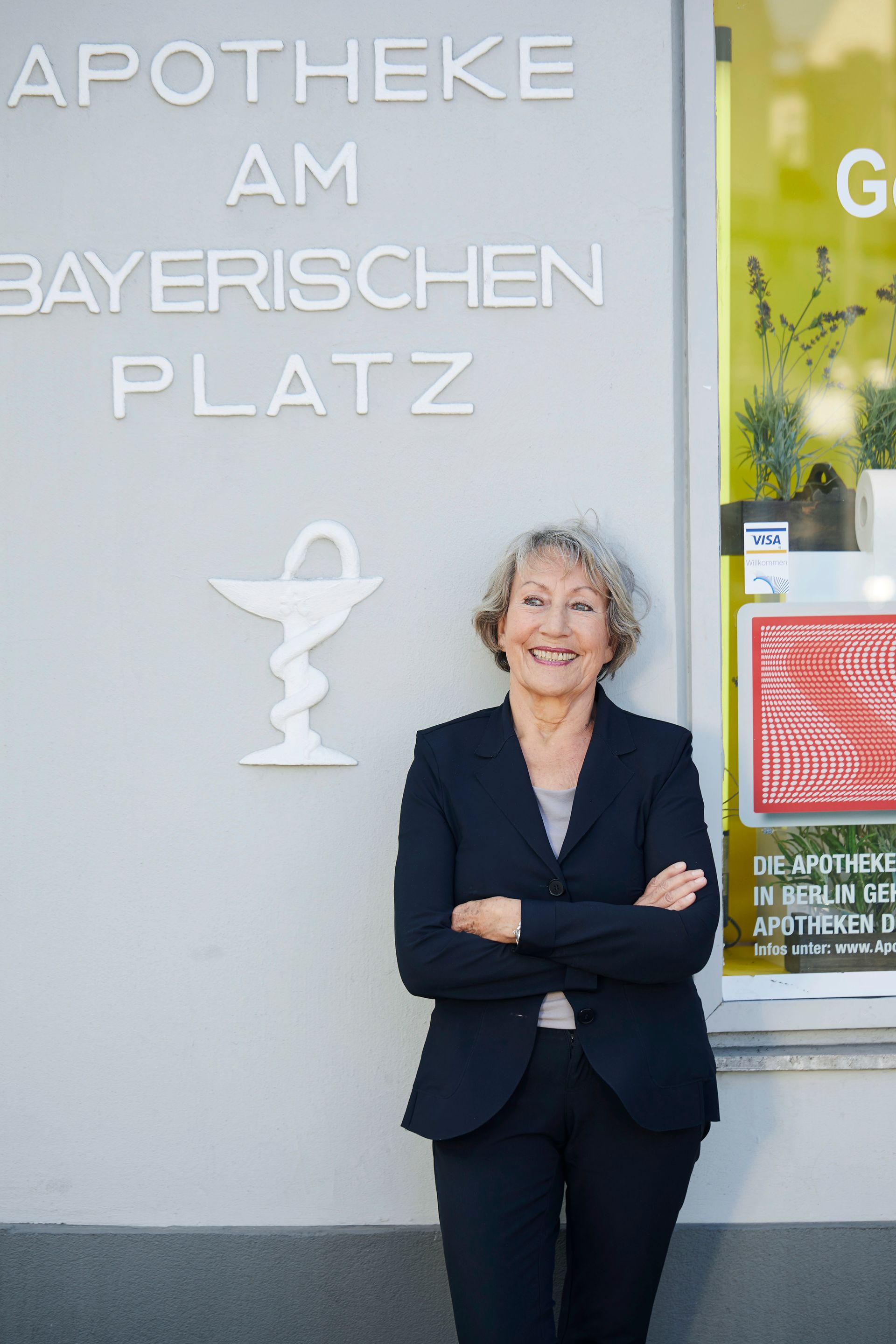 A woman is standing in front of a sign that says apotheke am bayerischen platz