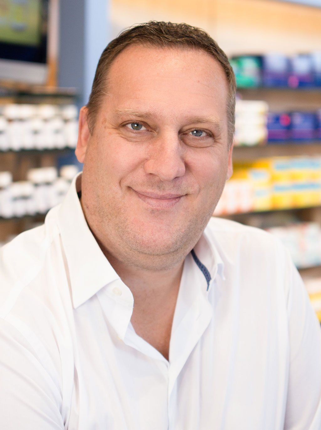 Ein Mann in einem weißen Hemd lächelt in einer Apotheke.