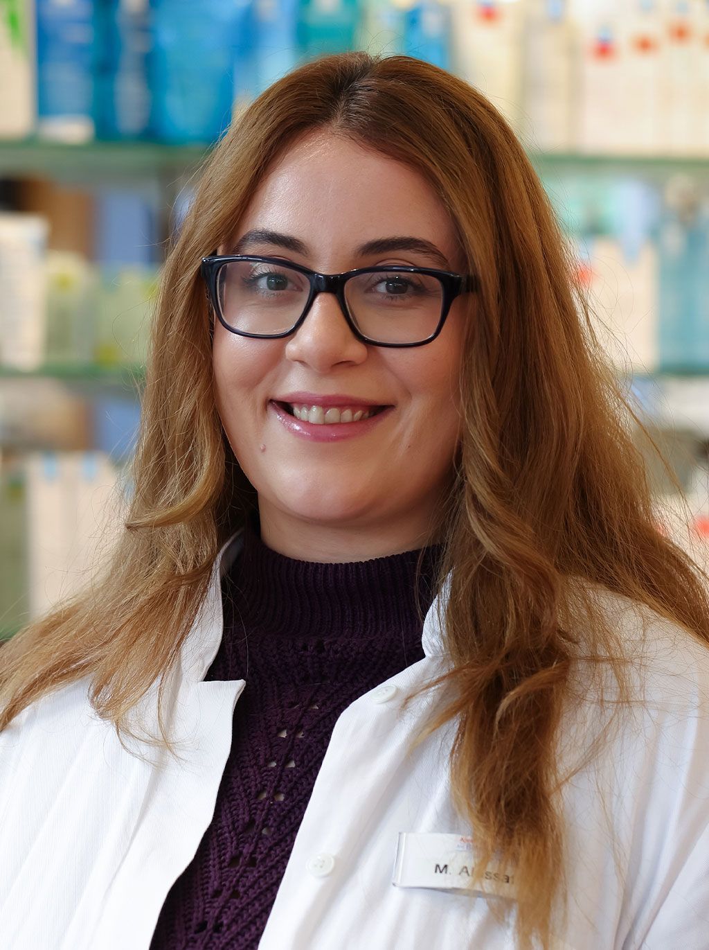 Eine Frau mit Brille und weißem Kittel lächelt in die Kamera.