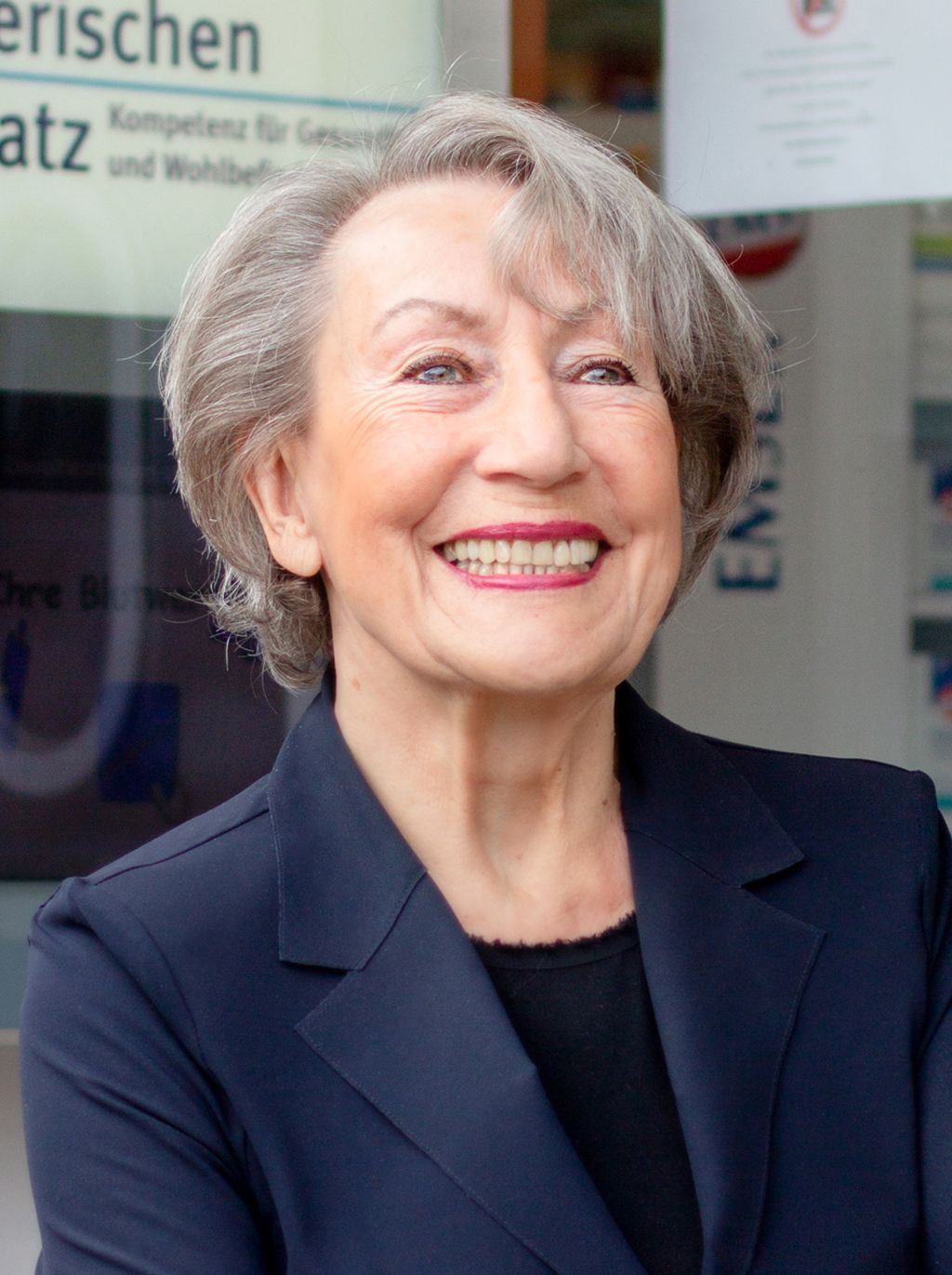 Eine Frau lächelt vor einem Schild mit der Aufschrift „Erischen“