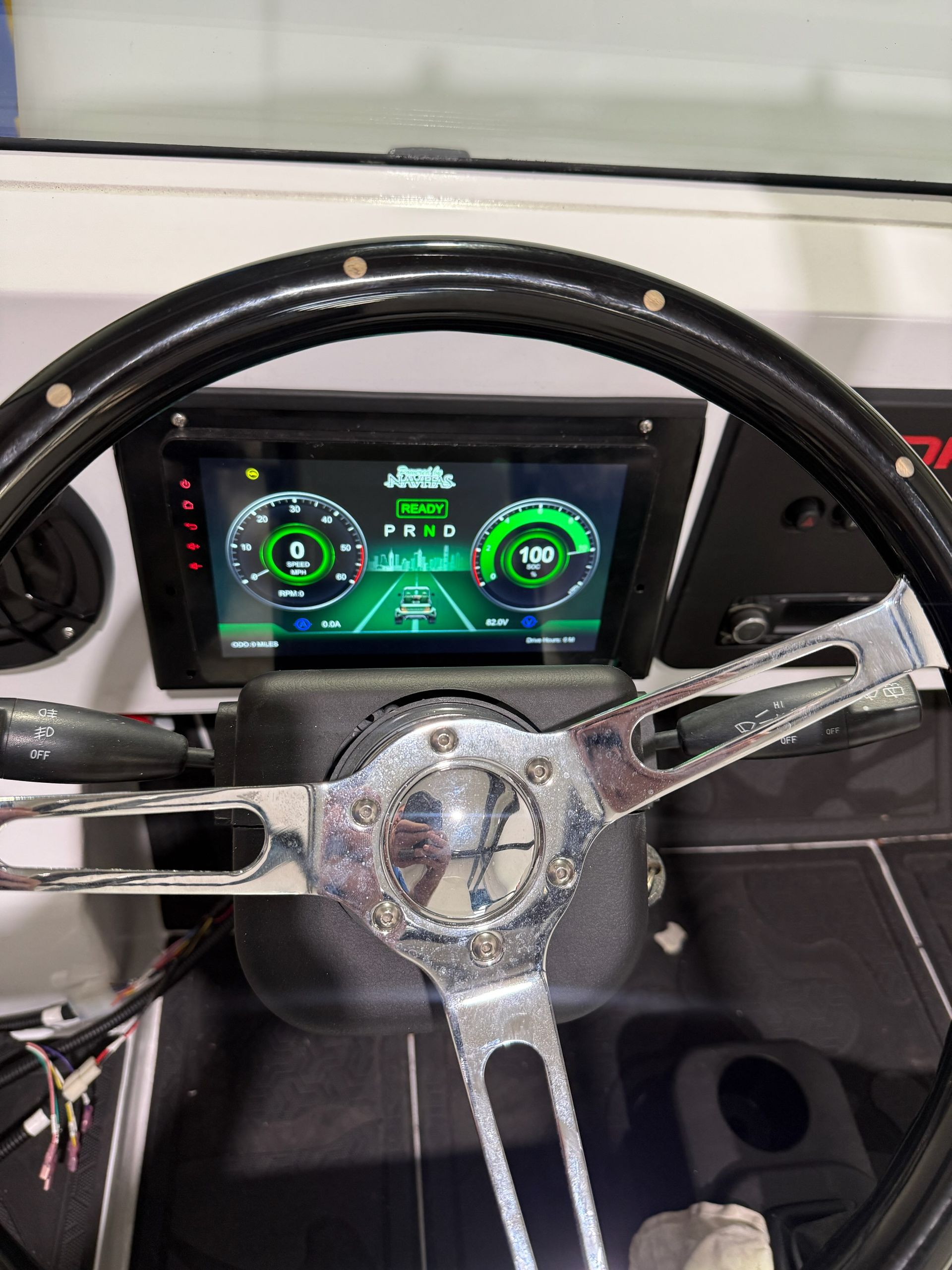 Steering wheel with digital dashboard displaying speed and driving information.