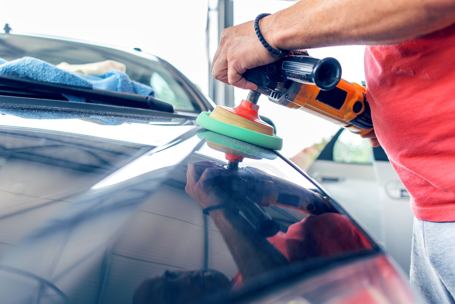 A man is polishing a car with a machine.
