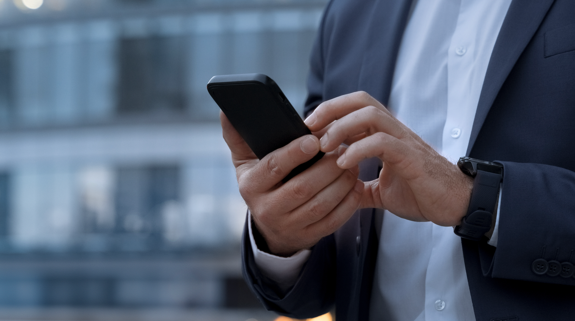 A man in a suit is using a cell phone.